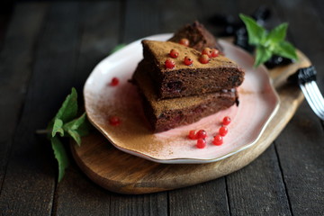 chocolate cake with prunes and cranberries on a dark wooden background.