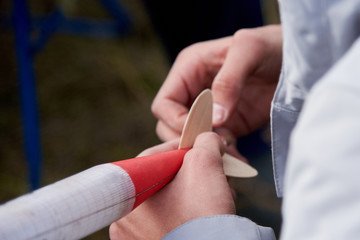 The guy holds in his hands a model of a rocket and prepares it for flight.