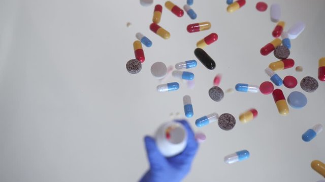 Different types pills falling on transparent surface.  Medicine, drugs, pills, capsules falling in slow motion.