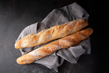 Fresh hot two baguettes on dark background. Top view.