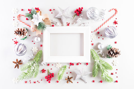 Christmas holidays composition Top view of white picture frame with gift box, Christmas tree decoration and red berries on white background with copy space for text.