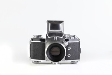 The old German 35 mm SLR film camera with lens 58 mm lens on a white cement background.