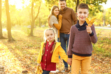 Happy children with parents resting in autumn park