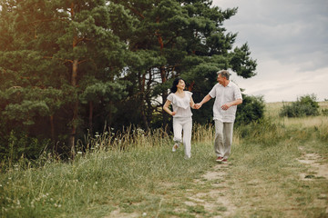 Fototapeta premium Adult couple in a summer field. Handsome senior in a white shirt. Woman in a white blouse