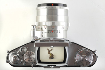 The old German 35 mm SLR film camera with lens 58 mm lens on a white cement background.