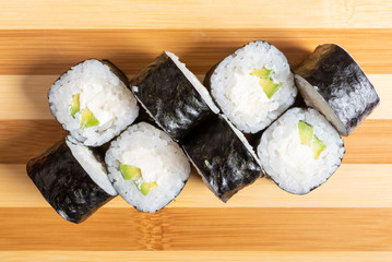 Sushi, maki, with curd cheese and avocado. On the plank.