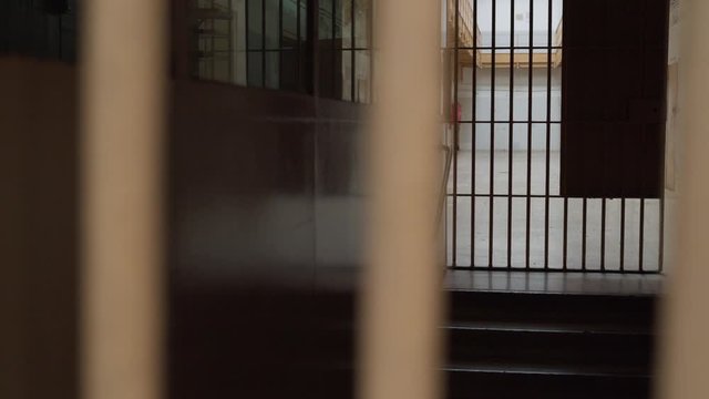 view of prison corridor through metal bars. camera moves from left to right