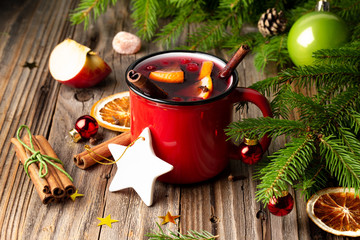 Holiday winter mulled Wine with orange, apple, cinnamon, cranberry and spices in red mug on the...