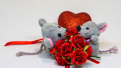 Saint Valentine's day. Lovely gray mouse gives rose to his girlfriend on the background of the decorative heart.