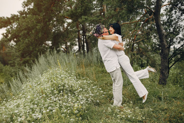 Adult couple in a summer field. Handsome senior in a white shirt. Woman in a white blouse