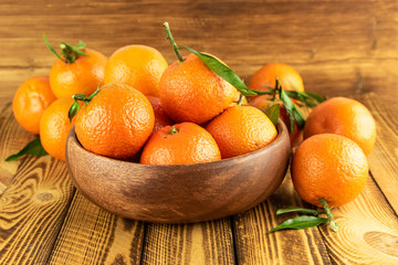 organic mandarin fruit in wooden bowl on wooden table