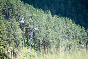 summer mountain landscape high in the mountains, tall pine trees and ski lift 