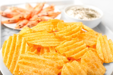Plate with tasty potato chips and shrimps on table, closeup