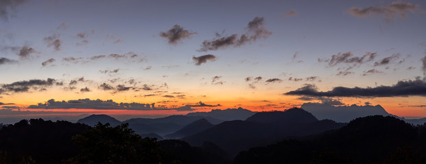 Layers of mountains line at sunset or sunrise with colorful sky panorama.