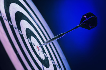Dartboard with hit bullseye on dark color background, closeup
