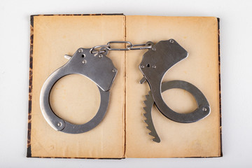 Old books and metal handcuffs. Literature and prison for bad words.