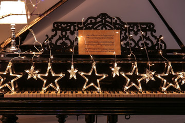Piano with glowing Christmas garland in room