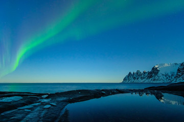 Fototapeta na wymiar Northern lights, Aurora Borealis, Devil Teeth mountains in the background, Tungeneset, Senja, Norway