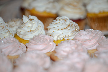 Vanilla cupcakes with vanilla frosting and gold sprinkles on dessert table