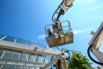 worker of Professional Facade Cleaning Services washing a galss roof