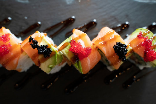 Top View of Sushi Roll with Salmon and Avocado on Top in Dark Tone / Japanese Food