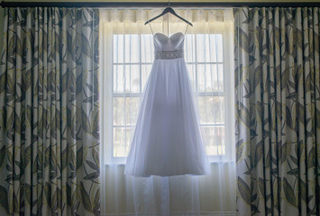 White wedding dress on hanger hanging in window