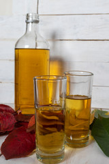 Bottle and glasses of brandy on the background of autumn leaves