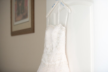 White wedding dress on hanger hanging from door