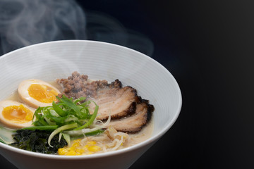 Hot delicious Japanese ramen noodles with pork egg corn scallions and seaweed in black background. Copy Space.