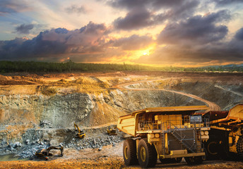 Yellow dump truck loading minerals copper, silver, gold, and other  at mining quarry.