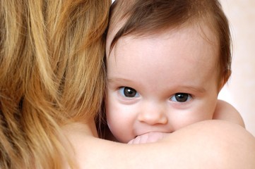 Cute little baby smiling on mothers shoulder