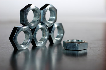 Close-up of a pyramid of five chrome metal nuts