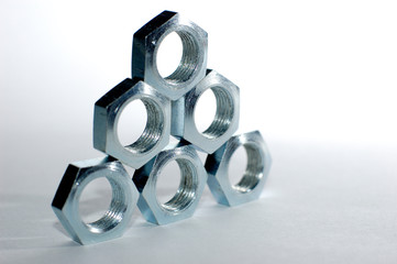 Close-up of a pyramid of five chrome metal nuts
