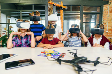 Modern technologies in a smart school. Clever caucasian pupils use virtual reality glasses for education.