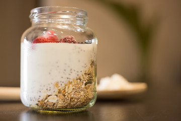 Healthy yogurt based on Kefir grains with red fruits, chia and granola over wooden table