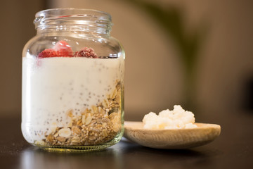 Healthy yogurt based on Kefir grains with red fruits, chia and granola over wooden table