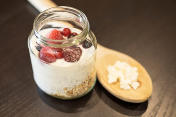 Healthy yogurt based on Kefir grains with red fruits, chia and granola over wooden table