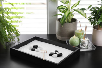 Beautiful miniature zen garden, candles and incense sticks on black table indoors