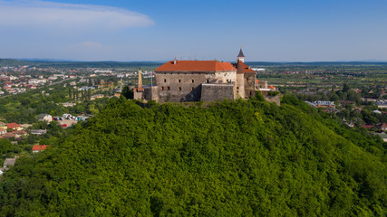 Obraz premium Picturesque view to the Palanok Castle with the red roofs under the blue sky in Mukachevo, Transcarpathian region in Ukraine. Aerial drone photo.