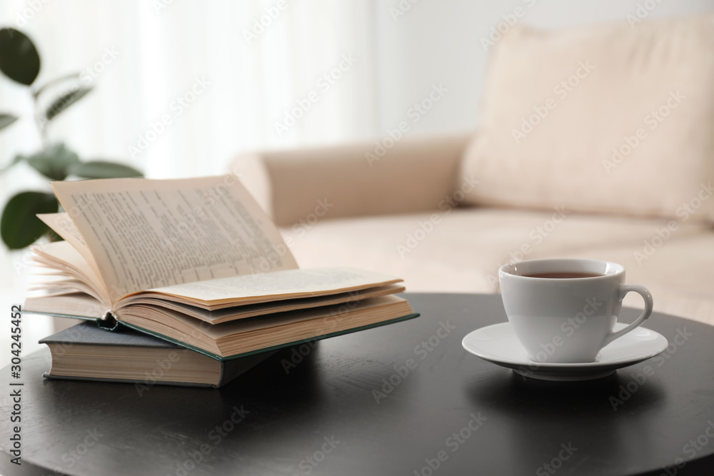 Sticker Books and cup of tea on table near modern sofa indoors. Home interior