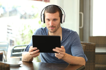 Serious man with headphones using a tablet in a bar