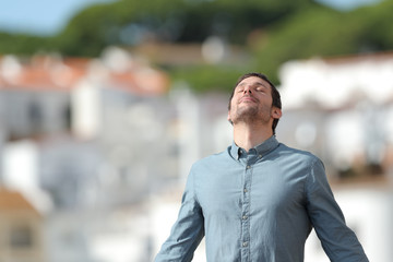 Fototapeta premium Relaxed man breathing deep fresh air in a rural town