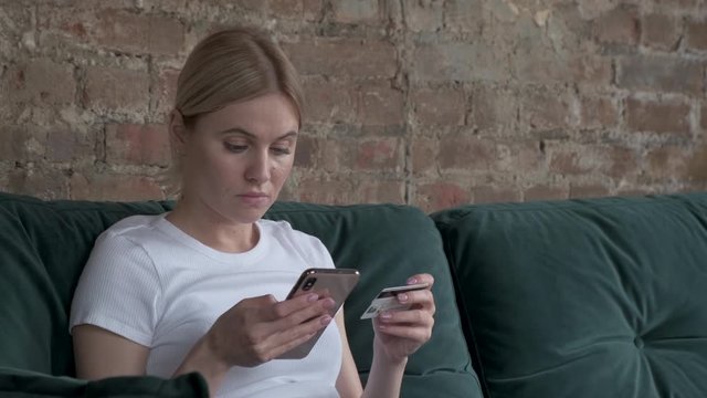 Close-up woman buys online shopping at home with card and phone. Young happy woman type entering master card number books. Buying, female.