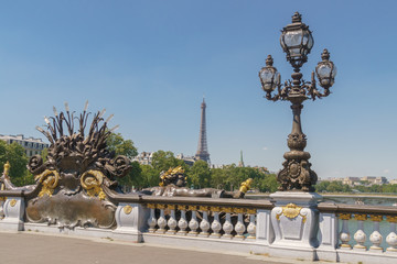 Fototapeta na wymiar Pont Alexandre III details with the Eiffel Tower in the background, with blue sky