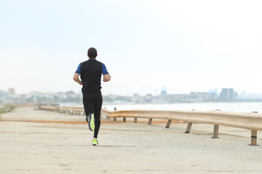 Back view of runner jogging on the beach