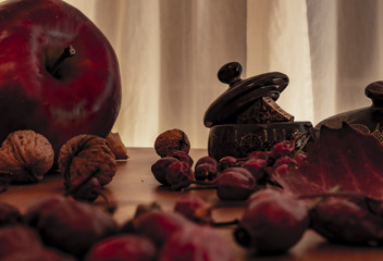 Christmas candles, red apples, cones and spices on rustic wooden background with  Balls and Christmas lights. Close up, selective focus 