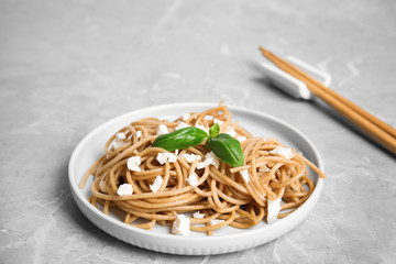Tasty buckwheat noodles with chopsticks on light grey table
