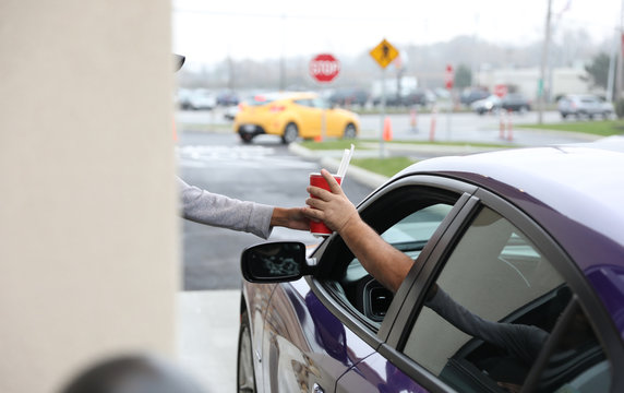 A drink with straws is delivered through a drive-thru