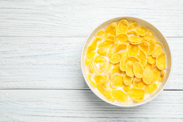 Tasty corn flakes with milk on white wooden table, top view. Space for text