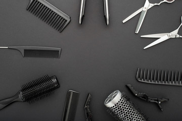 Flat lay composition with Hairdresser tools: scissors, combs, hair iron on black background with copy space for text in center. Frame. Hairdresser service. Beauty salon service. Hairdresser Set.